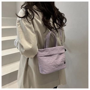 Detail of light purple pleated texture bucket bag with metal logo and shoulder strap