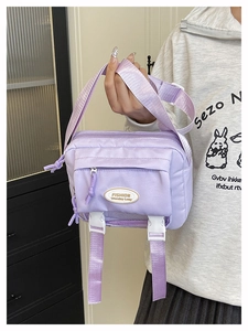 Detail of lavender nylon crossbody bag with zipper pocket and fashion patch logo