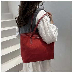 Close-up of red suede tote bag with brand tag on outdoor stairs showing large capacity
