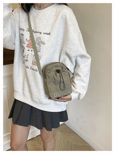 Detail of khaki drawstring crossbody bag featuring white Duoning embroidery and nylon texture