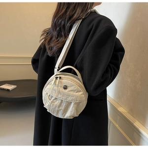 Close-up of a small round nylon crossbody bag with adjustable wide fabric strap