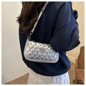 Detail of silver quilted underarm bag featuring rhinestone star and metallic finish