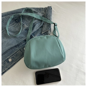 Detail view of a mint green shell bag with adjustable strap and casual accessories