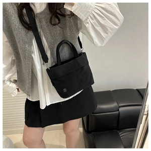 Close-up of black canvas mini bucket bag with silver logo and adjustable shoulder strap