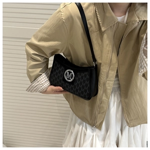 Close-up of black handbag featuring M-pattern fabric and silver circular metal logo