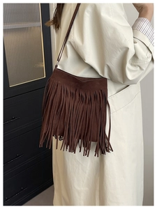 Detailed view of dark brown suede shoulder bag with dense bohemian style fringes