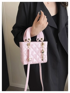 Close-up of pink quilted patent leather mini bag with gold key charm and fine strap