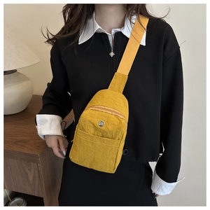 Close-up of a vibrant yellow nylon crossbody bag with a circular M-logo and wide strap
