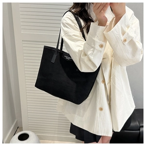 Detail of minimalist black canvas tote bag with slim shoulder straps for daily commuting