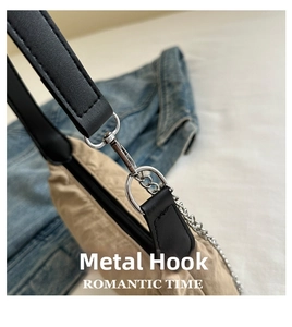Detail of silver metal hook and black leather strap on a beige nylon crossbody bag