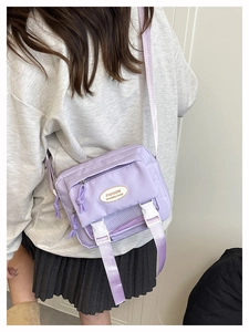 Detail of light purple nylon messenger bag with front buckles and woven shoulder strap