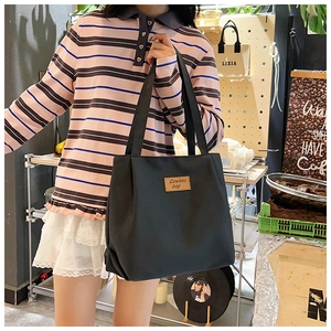 Detail of black canvas tote bag showing large capacity and brown cowboy leather label