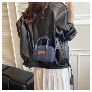 Mini denim pillow bag with brown leather patch shown on model in street style