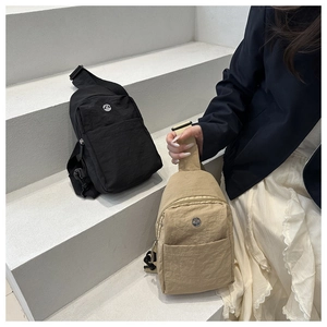 Détails de sacs bandoulière en nylon kaki et noir avec logos ronds sur des marches
