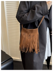 Brown fringe crossbody bag detail on black trench coat for a retro bohemian autumn look