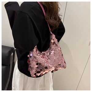 Detail of pink sequin crescent bag showing shimmering texture on a shoulder strap model