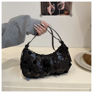 Detail of glossy black sequins on a crescent-shaped shoulder bag with metallic buckle