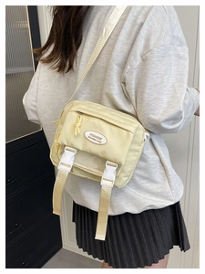 Detail of cream nylon crossbody bag featuring double buckles and fashion letter patch