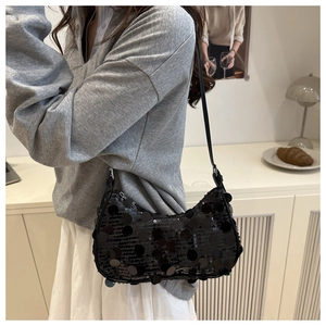 Detail of a black sequin shoulder bag showing shimmering texture and sleek leather strap