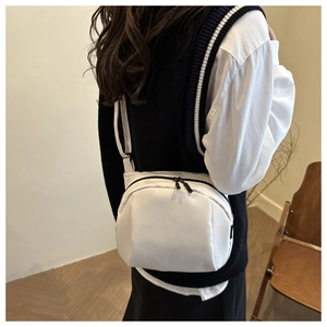 Minimalist white half-moon crossbody bag with black dual zippers shown on model