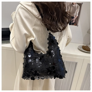 Détail du sac cabas sous le bras à paillettes noires montrant sa texture brillante
