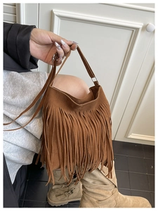 Detailed close-up of brown suede fringe saddle bag with long tassels in bohemian style