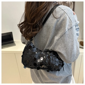Detail of sequin shoulder bag on model showing large reflective black sequins and strap