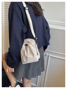 Détail de la bandoulière en nylon beige avec cordon, broderie et fermeture à corde