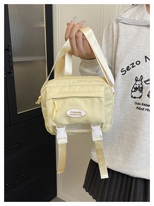 Close-up of yellow nylon crossbody messenger bag with fashion logo and buckle details
