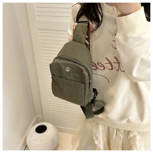 Close-up of olive green crossbody bag with metallic logo and textured nylon finish