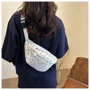 Close-up of white corduroy waist bag with brown heart and bow print patterns