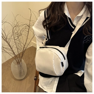 Detail of white nylon shell bag with FANYISSA brand label and black zipper closure