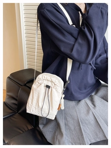 Détail du sac bandoulière blanc en nylon avec étiquette orange et logo imprimé élégant