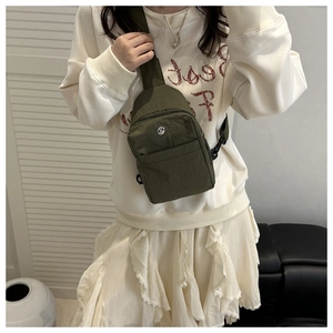 Olive green nylon crossbody bag detail showing metallic M logo and adjustable strap