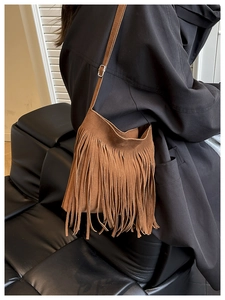 Detail of brown faux suede bucket bag with long fringe tassels and adjustable strap
