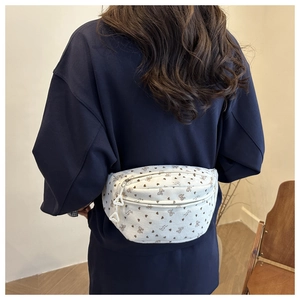 Detail of white corduroy waist bag with floral bow pattern worn on model's back