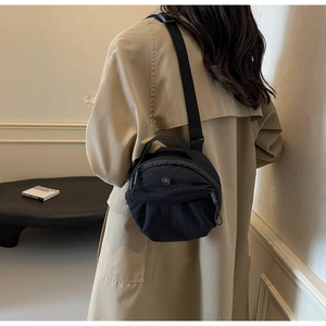 Model view of black nylon crossbody bag with dual zippers and metallic M logo detail