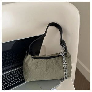Detail of olive green nylon shoulder bag featuring chic ruched texture and silver chain