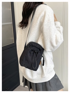 Détail du sac seau noir à cordon montrant le logo de la marque et la tirette tissée