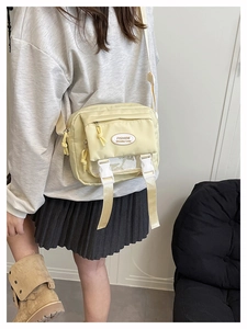 Detail of light yellow nylon crossbody bag with white buckles and mesh window
