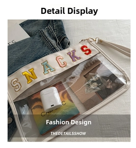 Detail of transparent PVC makeup bag with embroidered SNACKS lettering and white leather trim