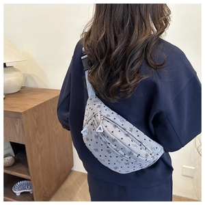 Détail d'un sac bandoulière gris à motifs cœurs porté par un mannequin, vue de dos