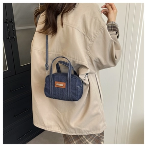 Close-up of mini vintage denim boston bag with contrast stitching and leather tag detail