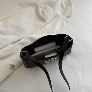 French vintage brown monogram underarm bag with silver M logo on a white suit background
