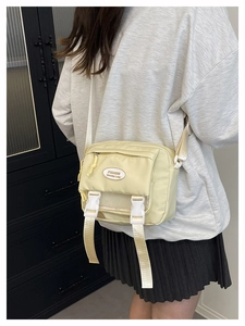 Detailed close-up of cream yellow nylon messenger bag with buckle closure and mesh pocket