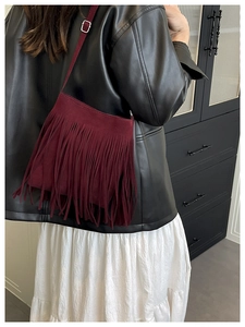 Detail of burgundy fringe crossbody bag with adjustable strap and retro suede finish