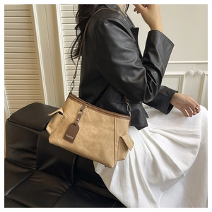 Dettaglio borsa hobo kaki con tasche laterali ed etichetta fashion indossata
