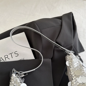 Sac à bandoulière chic à paillettes argentées avec lanière sur un blazer noir