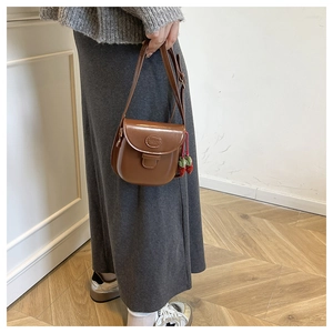 Detail of brown vintage faux leather mini crossbody bag featuring a strawberry pendant