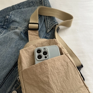 Borsa a tracolla minimalista beige in nylon con tracolla regolabile su sfondo denim